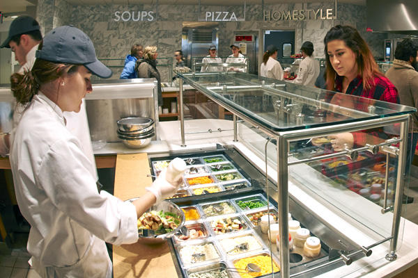 cafe laura workers serving customers; signs in background say "soups," "pizza," and "homestyle."